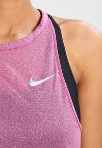 Camiseta deportiva rosa sin mangas con un patrón texturizado, que presenta una capa interior negra y un logo de Nike plateado en el frente.