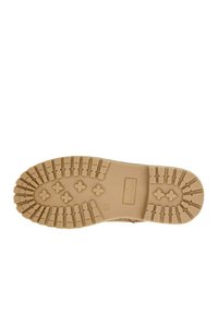 Semelle de botte en caoutchouc couleur fauve avec des rainures profondes, incluant des motifs croisés et rectangulaires, conçue pour la traction et la durabilité.
