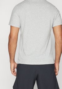 Camiseta gris de manga corta hecha de suave algodón, con cuello redondo y un corte relajado, presentada por la parte de atrás.