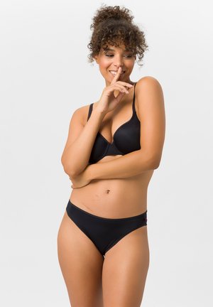 Schwarzes Lingerie-Set mit einem nahtlosen BH mit dünnen verstellbaren Trägern und einem passenden, niedrig sitzenden Slip, beide aus glattem Stoff.