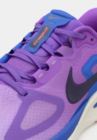 Μωβ αθλητικό παπούτσι Nike με άνω μέρος από δίχτυ, υφασμένα πάνελ και μπλε λεπτομέρεια. Διαθέτει μαύρο λογότυπο Swoosh και δομημένο σύστημα κορδονιών.