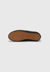 Shoe sole with a textured black upper and a light brown patterned rubber outsole, featuring a diamond grip design for traction.