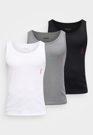 Drei ärmellose, gerippte Tanktops in Weiß, Grau und Schwarz, jeweils mit einem kleinen roten "HUGO"-Logo auf der linken Seite.