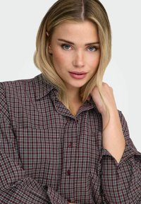 Camisa de cuadros burdeos con cuello abotonado, que presenta un bolsillo en el pecho y puños regulares, hecha de suave tela de algodón.