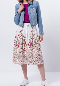 Kukkakuosisempi midi-hame valkoisena, jossa on vaaleanpunaisia ja vihreitä kuvioita, yhdistettynä vaaleansiniseen farkkutakkiin. Valkoiset lenkkarit viimeistelevät asun.