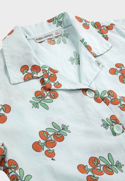 Chemise bleue claire pour enfants avec des grappes de tomates cerises rouges imprimées et des feuilles vertes, dotée d'un col et de boutons.