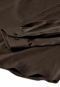 Cămașă închisă la culoare, maro, cu un aspect neted, având butoane negre și manșete pliate, ce evidențiază un design croit și linii clare.