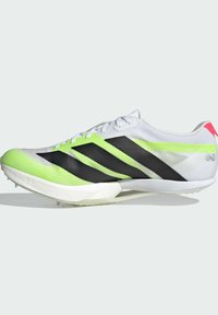 Chaussure de sport blanche avec des rayures latérales noires, des accents vert néon et une tige texturée. Présente une forme effilée et une semelle extérieure à pointes.