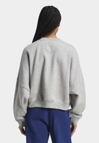Grå kortärmad sweatshirt med en mjuk yta, rund hals och avslappnade axlar. Har en enkel design och ribbad nederkant.