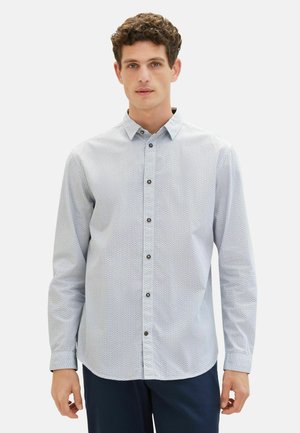 Camisa de botones azul claro con un patrón geométrico, de mangas largas y botones marrones. Tejido suave con un corte relajado.