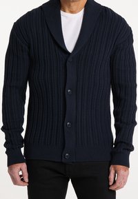 Námořnická pletená cardigan s šálovým límcem, vybavená pěti knoflíky, dlouhými rukávy a texturovaným materiálem.