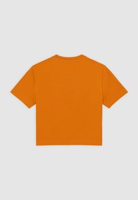 Camiseta de manga corta en brillante tela de algodón naranja con cuello redondo y espalda lisa. Presenta un corte holgado.