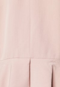 Vaaleanpunainen kangas, jossa on sileä pinta, jossa on pystysuorat saumat ja laskostettu alaosa lisäämään tilavuutta.