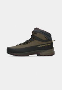 Tumši zaļi un melni augstās kalnu kājnieku zābaki, ar izturīgu zoli, pastiprinātu purngalu un dzeltenām auklām. Iekļauti zīmola elementi un mīkstinājums.