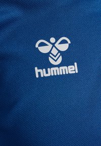 Blå sporttyg med en strukturerad mönstring och en vit Hummel-logga samt bi-design i centrum. Mjukt, andningsbart material.