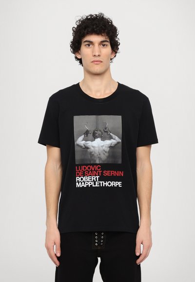 Schwarzes Baumwoll-T-Shirt mit einem grafischen Druck eines muskulösen Rückens und Text in Rot und Weiß, auf einem schlichten Hintergrund.