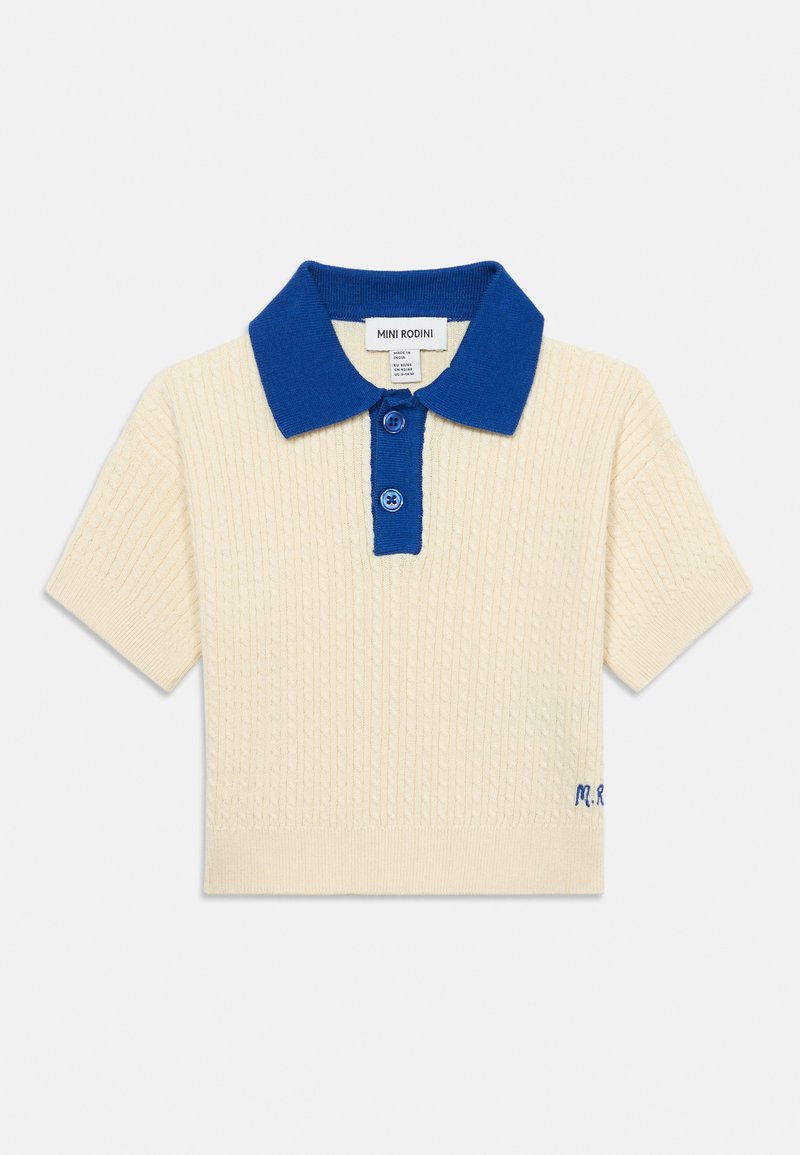 Polo en maille crème à manches courtes, col bleu et patte de boutonnage, avec une texture côtelée subtile et petites initiales brodées sur l'ourlet.