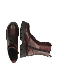 Un par de botas de cuero rojo oscuro con cordones y suelas negras gruesas, una bota mostrada desde la parte superior y la otra de lado.