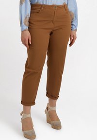 Braune Baumwollhosen mit umgeschlagenen Säumen, im Fünf-Taschen-Design und mit einem vorderen Knopfverschluss. Getragen mit hellen Espadrille-Wedges.