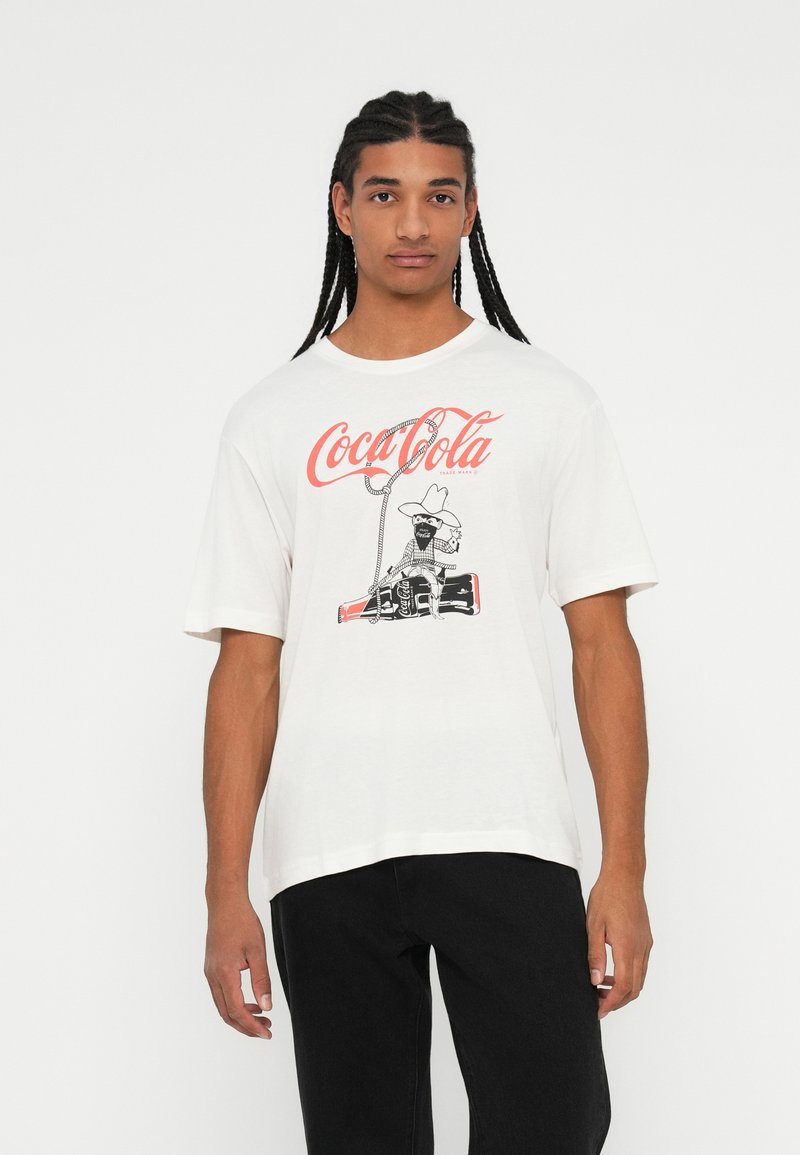 Valge puuvillane T-särk, millel on graafiline kujutis cowboy'st Coca-Cola pudeliga. Lühikesed varrukad, mugav lõige ja ümar kaelus.