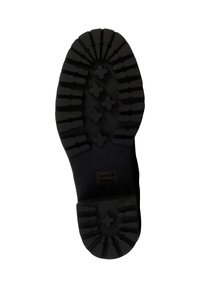 Suela de goma negra con surcos y patrones profundos, que presenta un diseño de cruz elevado. La forma es redondeada en la punta y plana en el talón.