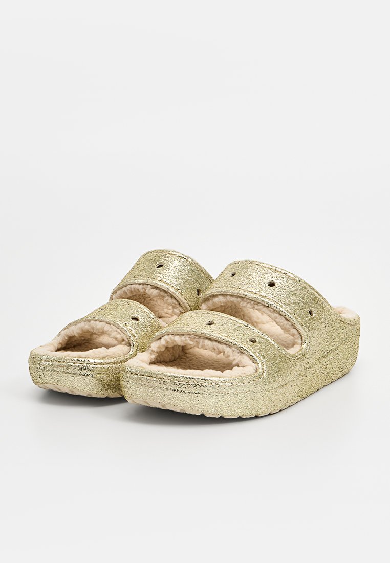Gouden glitter slippers met twee brede banden, zachte beige nepbont voering en een gestructureerde zool. Open teenontwerp met ventilatiegaten.