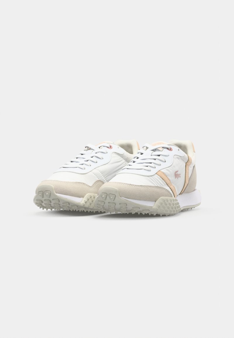 Weiße Sportschuhe mit einer strukturierten beigen Überlagerung, pinken Akzenten und grauen Gummisohlen mit einem Grip-Muster. Schnürdesign.