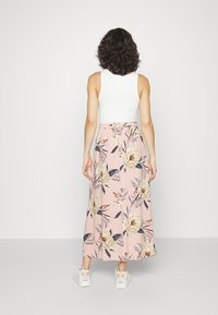 Maxi gonna blush pink con stampa floreale, caratterizzata da una vita elastica arricciata e un tessuto morbido. Abbinata a una canotta bianca e sneakers bianche.