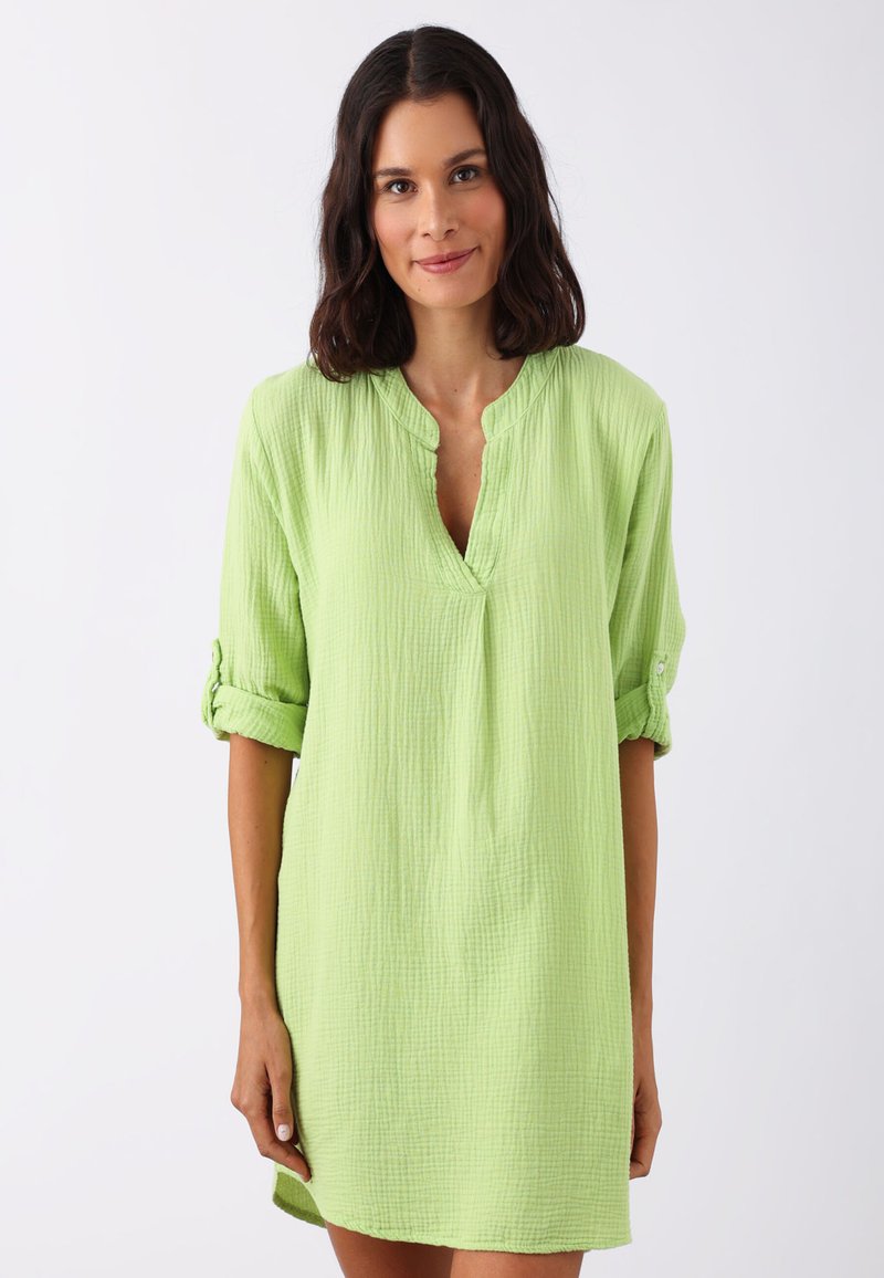 Robe vert clair texturée avec un décolleté en V et des manches retroussées. Fabriquée en tissu froissé, elle a une coupe ample et tombe au-dessus des genoux.