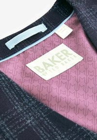 Svart tygkrage med ett texturerat mönster. Innerfoder i ljusrosa med en subtil geometrisk design. Etiketten säger "BAKER av TED BAKER."