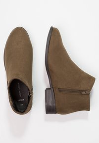 Botas de tobillo de ante marrón con puntera redonda, cierre de cremallera lateral y tacón apilado. Textura suave y diseño sencillo.