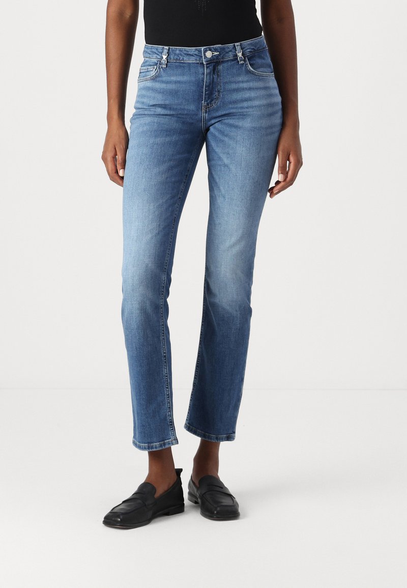 Jeans in denim blu chiaro con un design slim e gamba dritta, caratterizzati da cinque tasche e vita a media altezza.