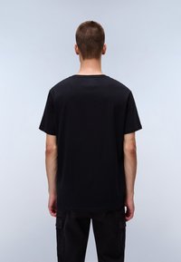 T-shirt en coton noir avec un col rond classique et des manches courtes, affichant une coupe décontractée et une texture lisse, porté avec un pantalon cargo sombre.
