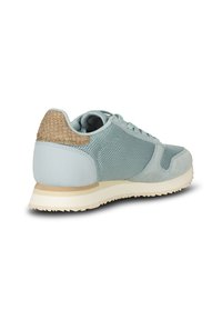 Zapatilla azul claro con parte superior de malla y ante, talón beige texturizado, cuello acolchado y suela de goma crema con un patrón de agarre texturizado.