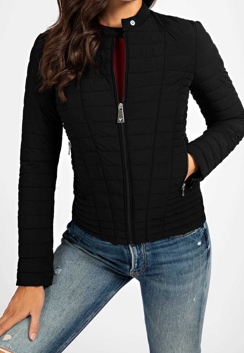 Giacca nera imbottita con colletto alto, zip frontale e tasche laterali. Tessuto strutturato con un design aderente e maniche lunghe.