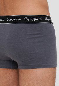 Sive katoen bokserice s crnim pojasom s bijelim prošivanjem logotipa "Pepe Jeans". Glatka tekstura, uski dizajn.