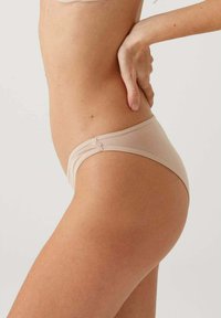Beige katoenen bikini ondergoed met een lage taille, een gladde textuur en minimalistische naaddetails. De zijaanzicht toont de pasvorm en bedekking.