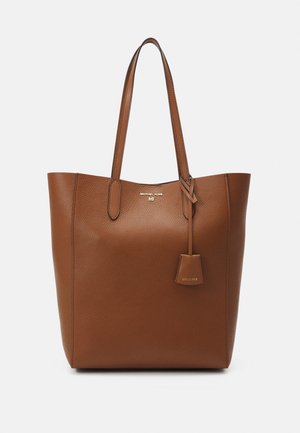 Sac cabas en cuir marron texturé avec deux longues anses et une petite étiquette suspendue, affichant le logo Michael Kors en lettres dorées.
