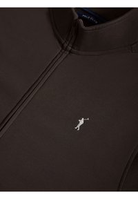 Tmavě hnědý pulover s čtvrt zipem, vyrobený z hladké látky. Obsahuje malé vyšívané logo golfisty v stříbrné barvě.