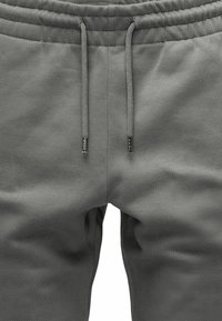 Graue Sweatpants mit elastischem Bund, Kordelzug und glattem Material. Verfügt über gestickte Details und subtile Seitennähte für eine gute Passform.