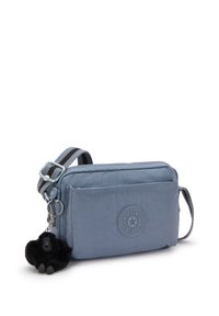 Borsa a tracolla blu chiaro realizzata in tessuto resistente. Presenta un'applicazione a patch rotondo con logo, un charm a forma di gorilla nero e una tracolla regolabile a righe.