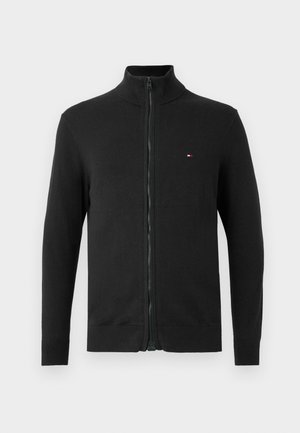 Cardigan preto com fecho frontal, feito em tecido de malha. Apresenta um colarinho alto, mangas longas e um pequeno logo em destaque no peito. Textura suave.