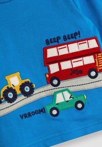 Tricou din bumbac albastru cu aplicații colorate de mașini și tractoare în roșu, verde și galben, cu text brodat "Beep Beep!" și "VRROOM!".