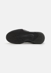 Semelle noire de chaussure de sport avec des motifs de bande de roulement texturés en zigzag et ondulés, présentant un grand logo Swoosh embossé au centre.