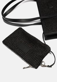 Zwarte gevlochten stoffen tas met een gestructureerd oppervlak. Voorzien van een leren label en een ritssluiting. Inclusief een afneembare schouderband en hardware-accenten.