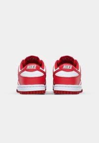 Nike sportcipők, piros bőr felsőrésszel, fehér részletekkel, párnázott gallérral és textúrált gumitalppal. A hátsó részen a Nike logó található.