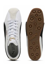 Baskets Puma avec une tige en cuir blanc, des accents en daim noir, une semelle extérieure en gomme texturée, et une semelle intérieure rembourrée étiquetée "SOFTFOAM".