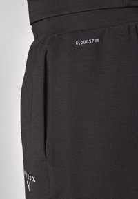 Schwarze Jogginghose mit Seitentaschen, aus weichem Material hergestellt. Verfügt über einen strukturierten Bund und ein weißes "CLOUDSPUN"-Logo auf der Vorderseite.