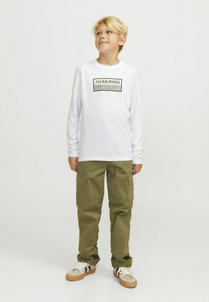 Weißes Langarmshirt mit einem schwarzen und grünen Markenlogo, kombiniert mit olivgrünen Cargo-Hosen mit Seitentaschen und beigen Sneakers.