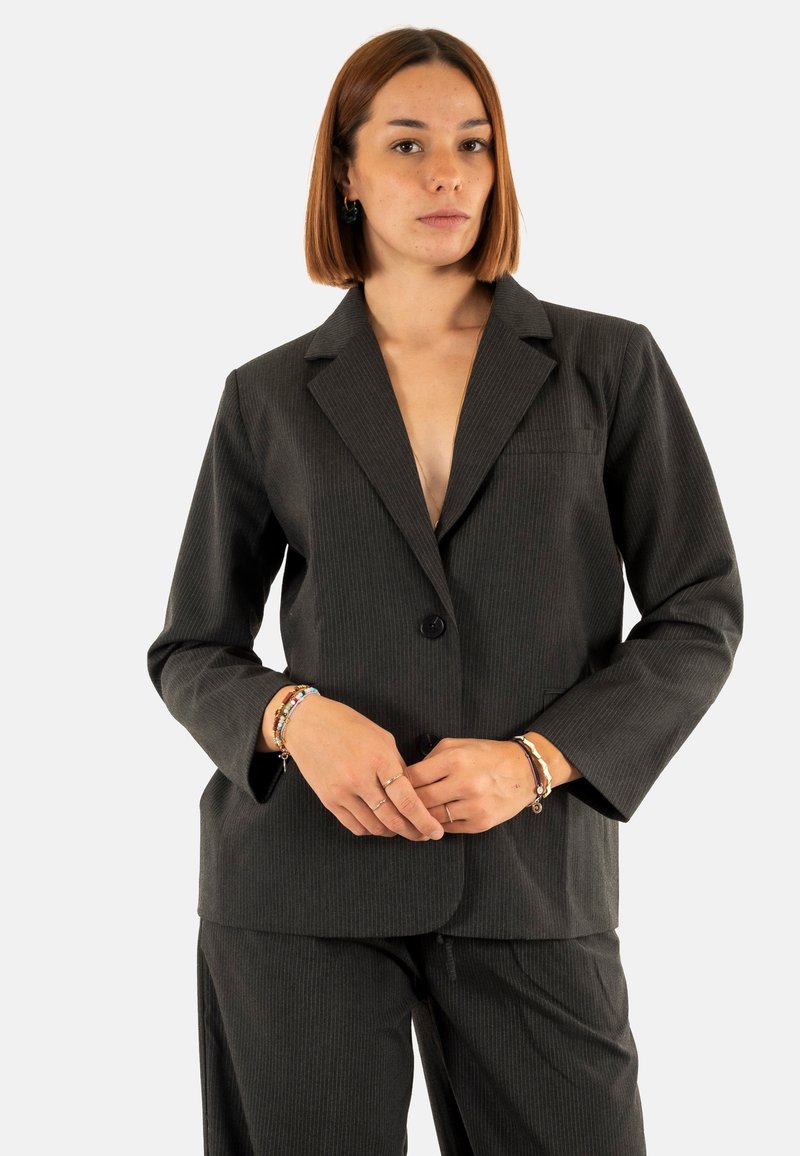Blazer nero a righe sottili con rever a punta, chiusura a un bottone e due tasche frontali. Realizzato in tessuto testurizzato.